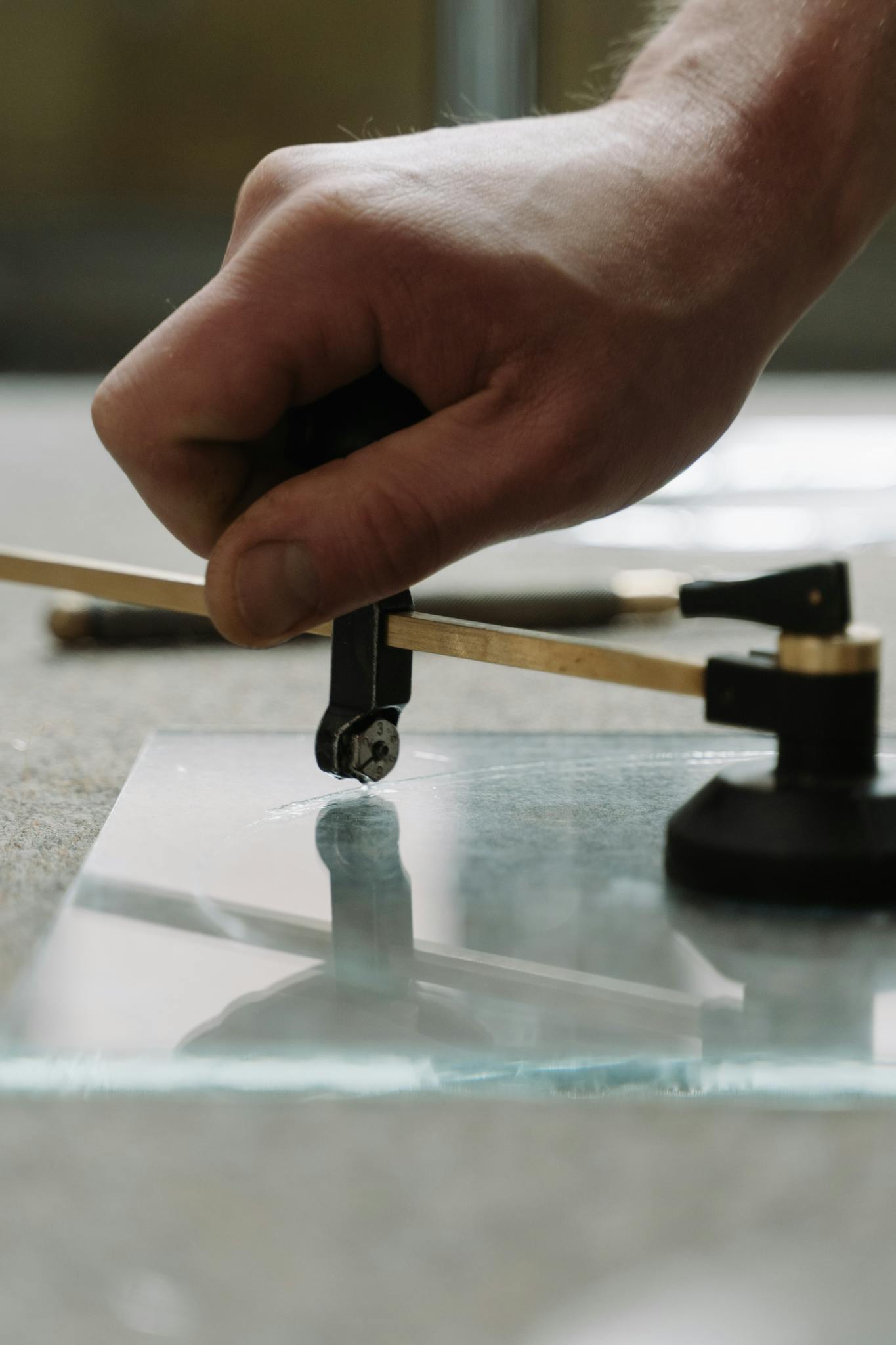 Close-up of skilled craftsman cutting glass with precision tool.