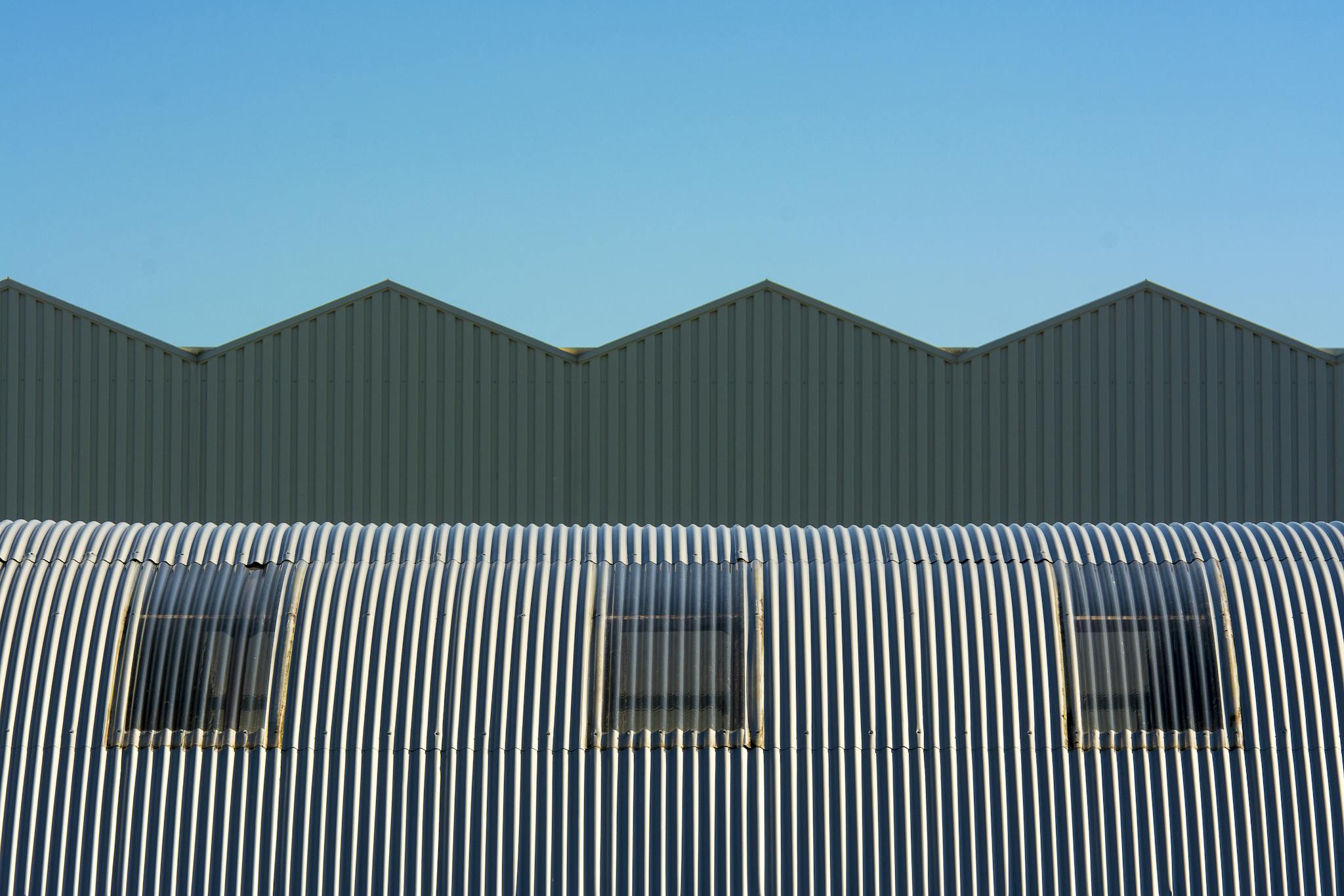 Industrial warehouse with corrugated and cylindrical roof design showcasing geometric structure.